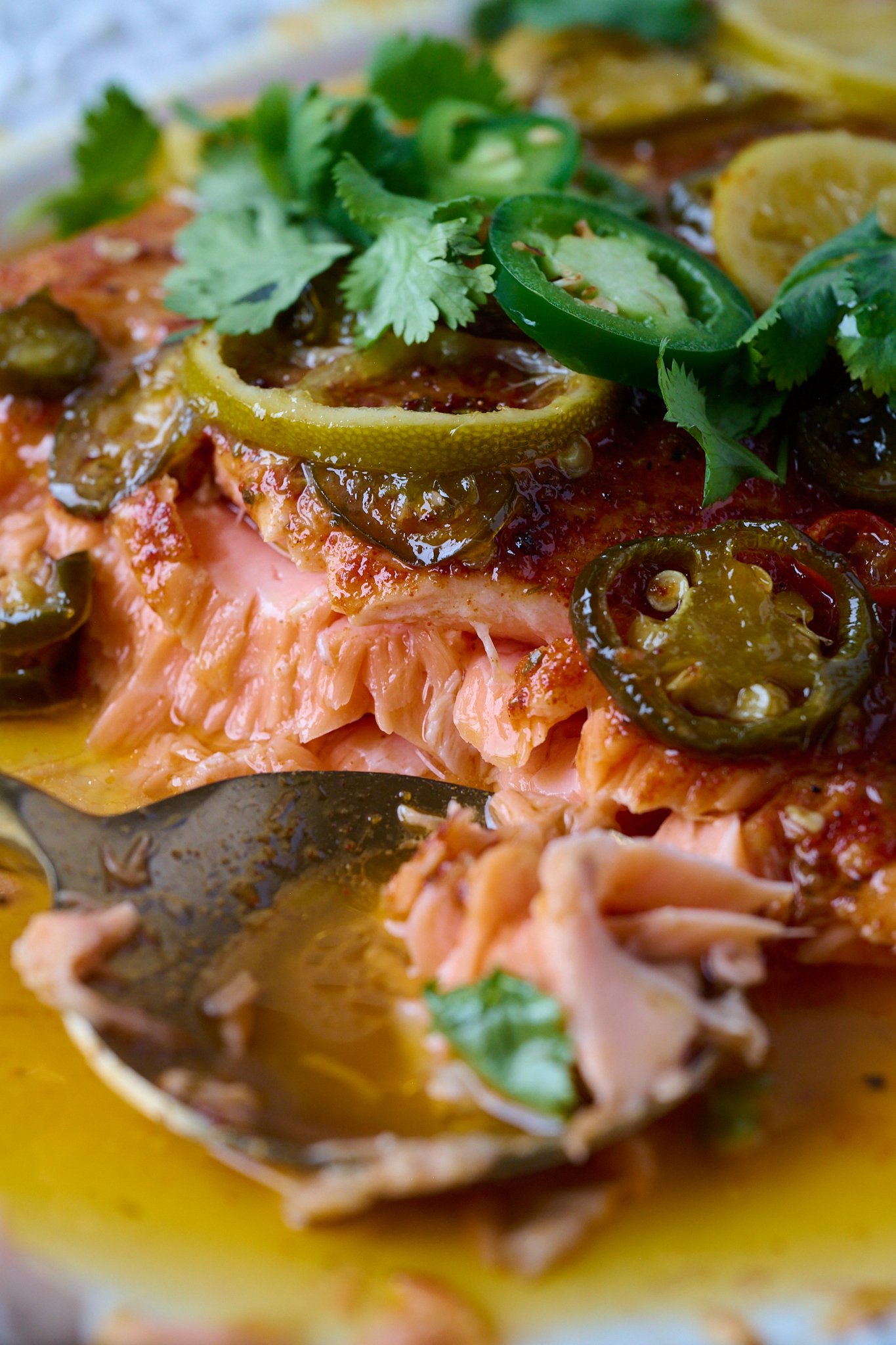 Hot honey roasted salmon has large piece taken out of it with gold spoon