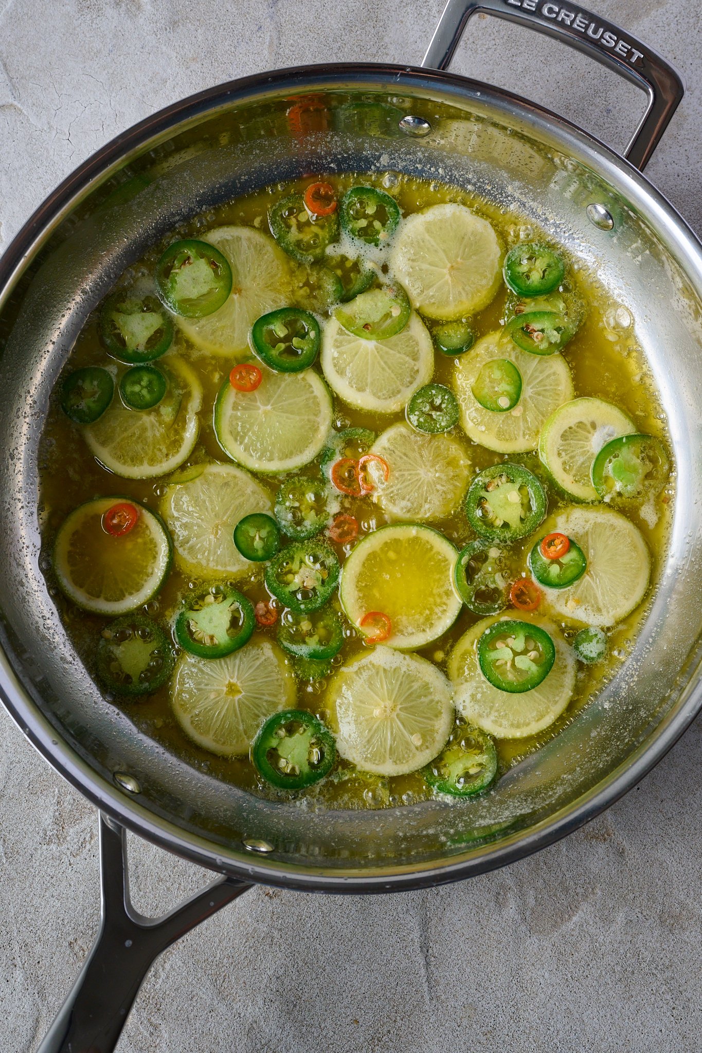 raw limes and jalepeno in large stainless steel pan with lots of butter. 