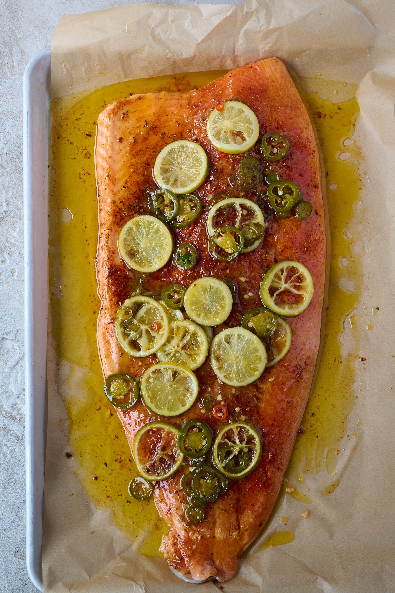 hot honey slow roasted salmon is in large baking tray and has not been baked. You can see the limes and jalepeno.
