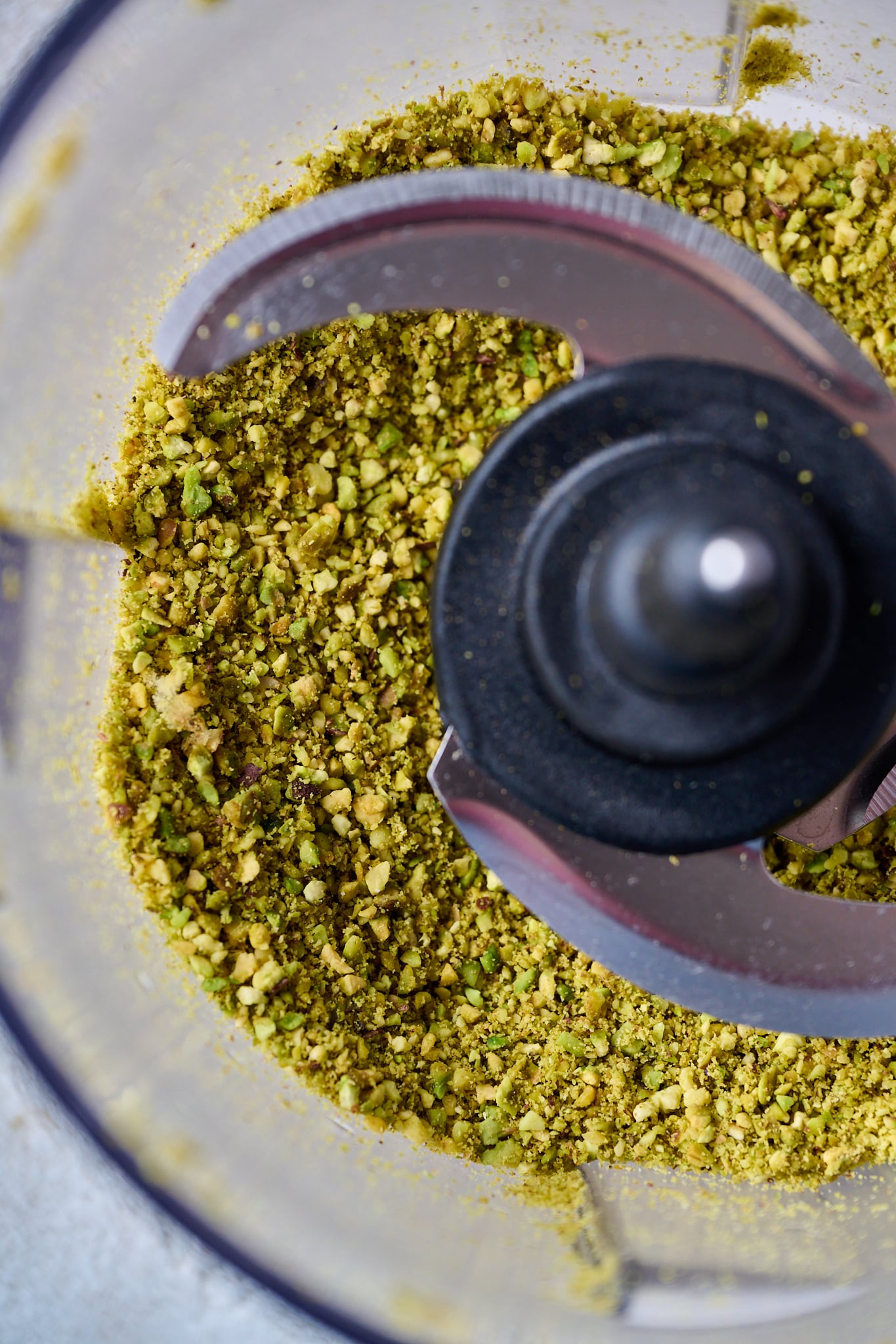 Finely ground pistachios are in a food processor.
