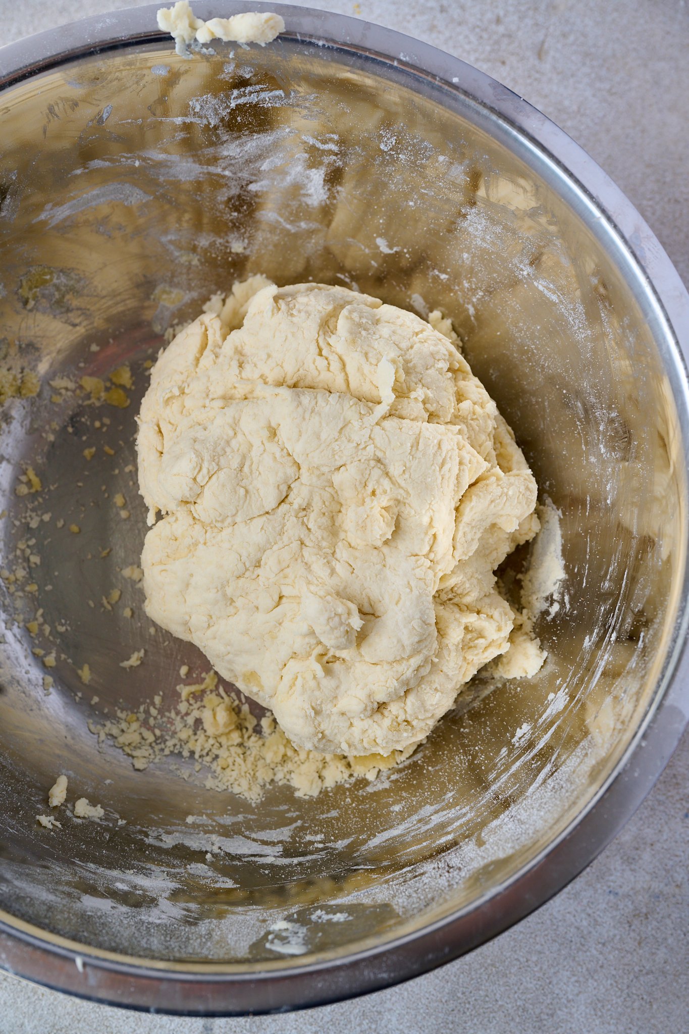 A shaggy ball of dough sits in a stainless steel bowl.