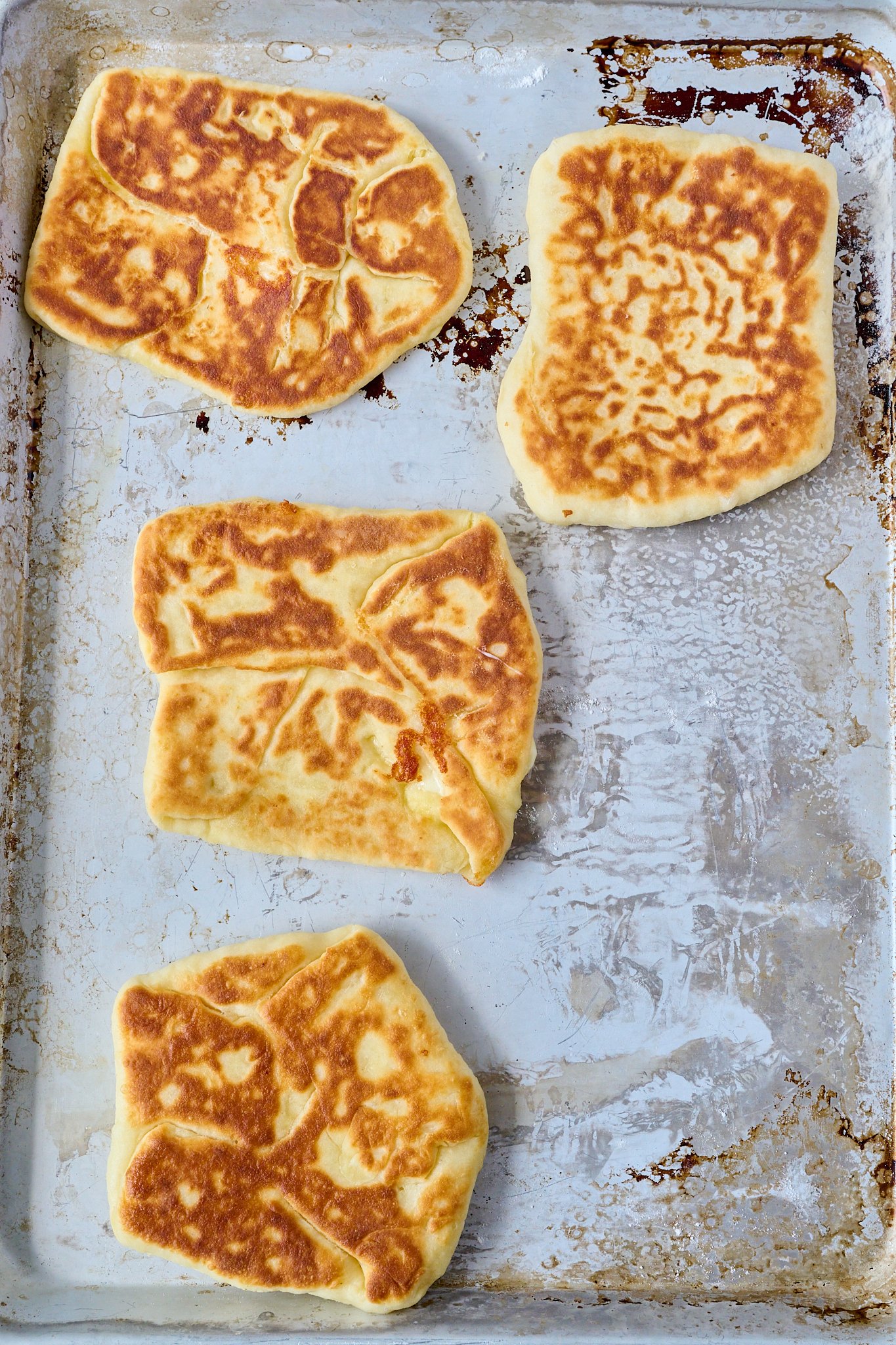 4 yoghurt flatbreads have been cooked and are golden on the outside. They sit on a baking tray.