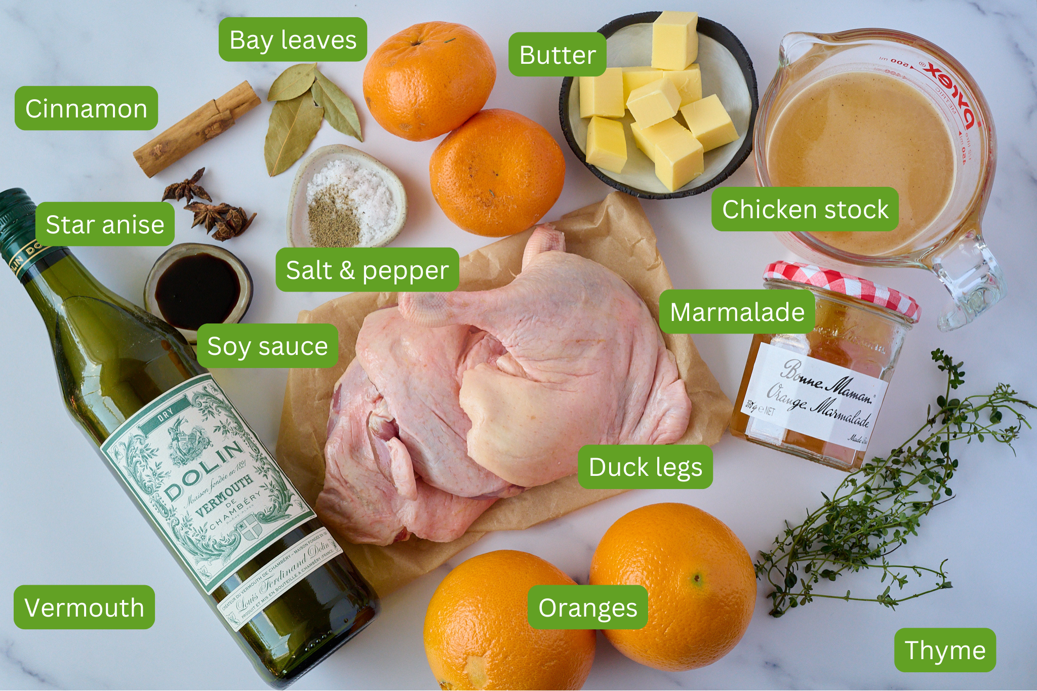 Ingredients for Crispy braised duck legs are shown. You can see bay leaves, cinnamon, star anise, vermouth, butter, oranges, chicken stock, marmalade, soy sauce, duck legs, thyme and salt and pepper.