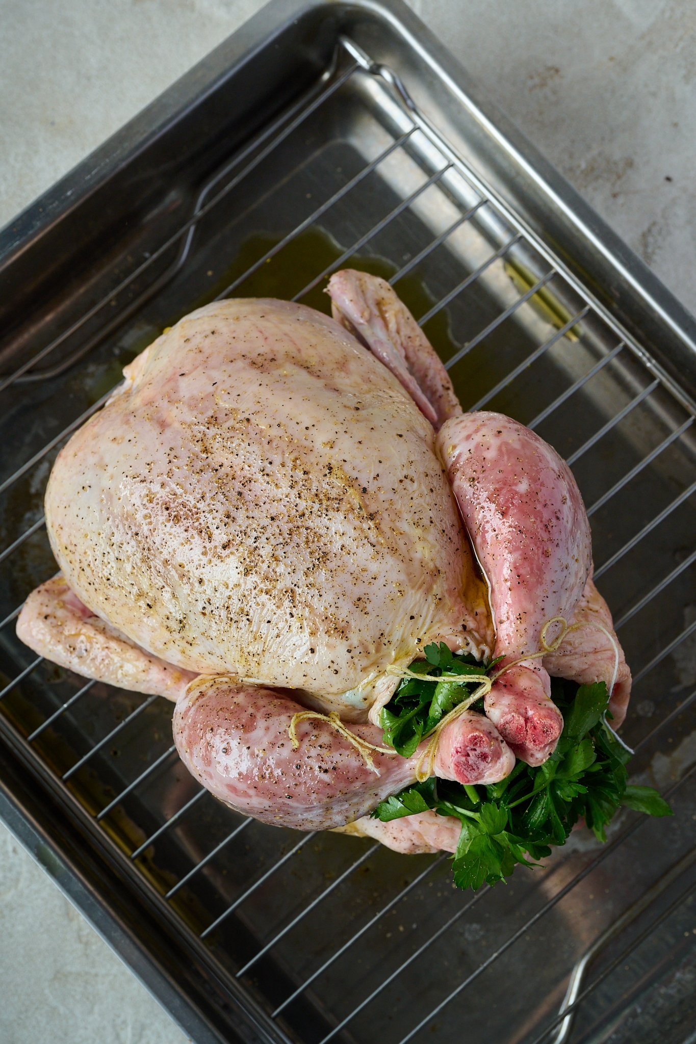 Whole chicken is raw and sitting on baking rack.