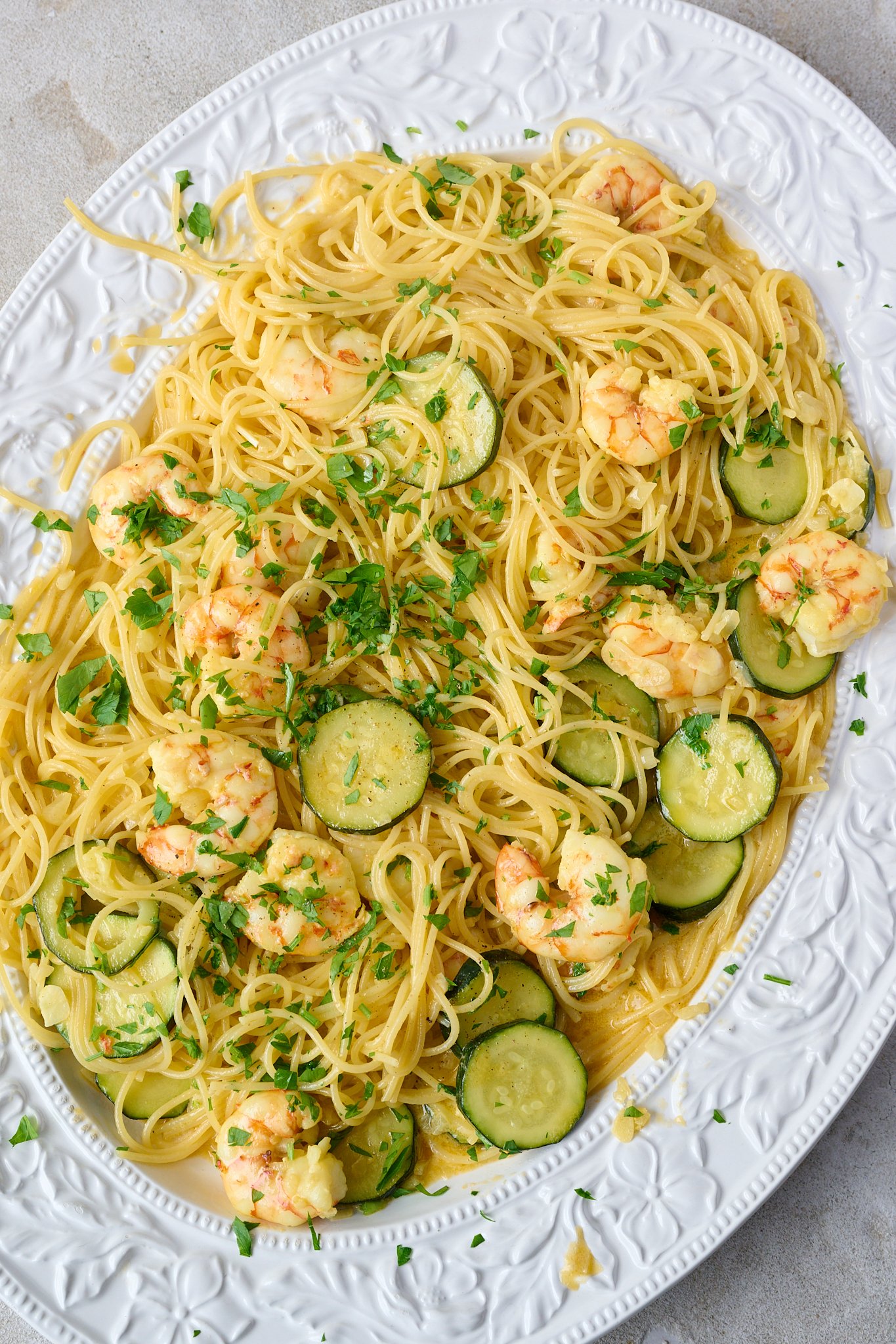 shrimp (prawn) and saffron spaghetti is in large white platter and has parsley sprinkled over top. 