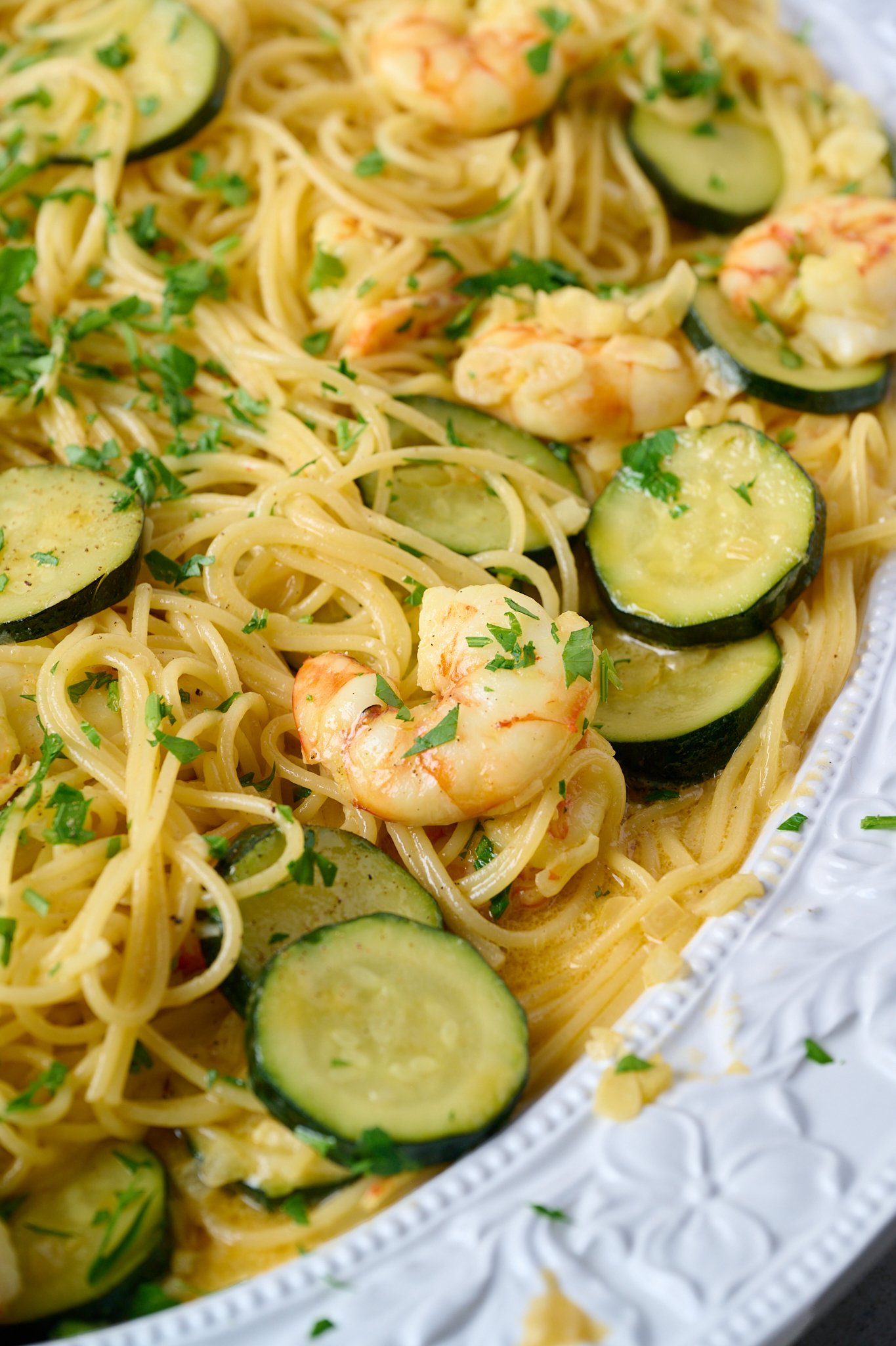 shrimp (prawn) and saffron spaghetti is in large white platter and has parsley sprinkled over top.