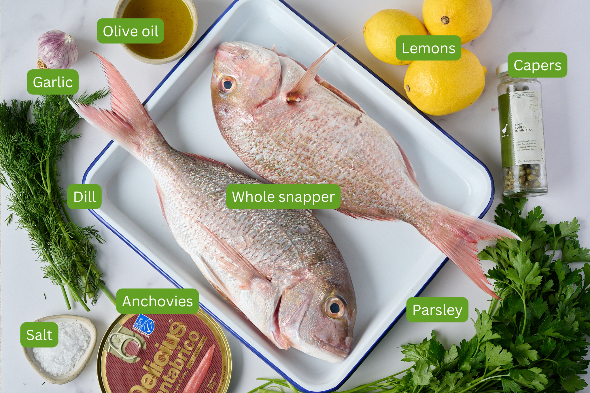 You can see all ingredients for whole baked fish with salsa verde. Ingredients include whole snapper, lemons, capers, garlic, olive oil, dill, salt, anchovies, parsley.