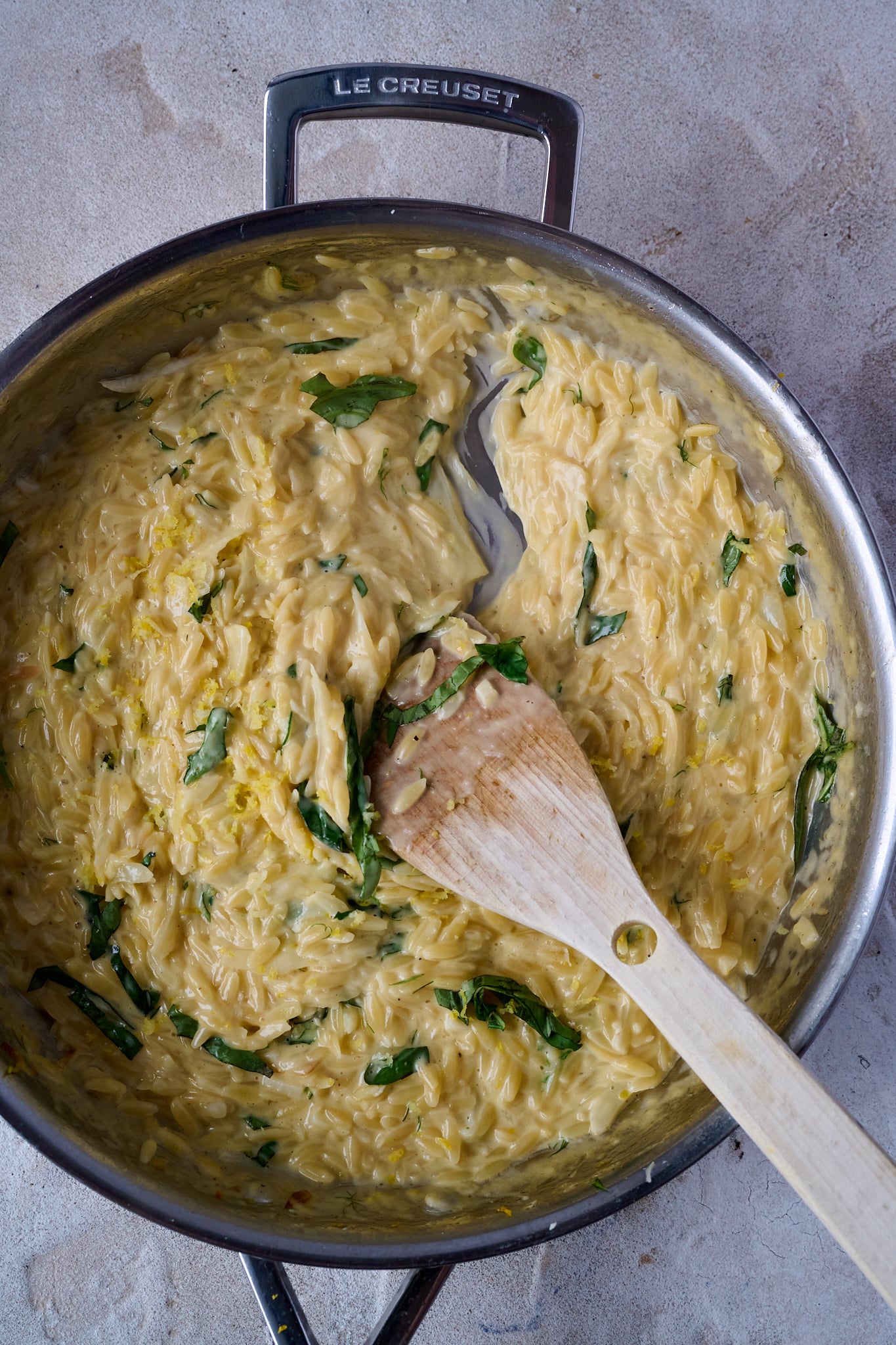 Caramelized Fennel One Pot Orzo Pasta is cooked and in large stainless steel pan with a wooden spoon sticking out of the pan.